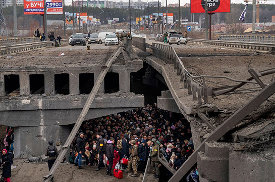 People crowd under a destroyed bridge as they try to flee the imminent threat of russians troops, 2022 / AP